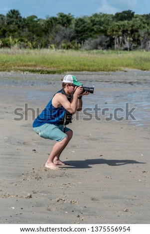 Young Male Photographer Taking Photos at the Beach on a Sunny Day
