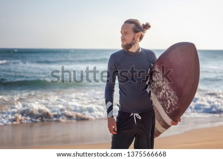 Young attractive sporty stylish man with a surfboard in his hands against the background of the ocean beach, active lifestyle sport freedom vacation travel concept
