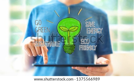 Green light bulb with young man using a tablet computer