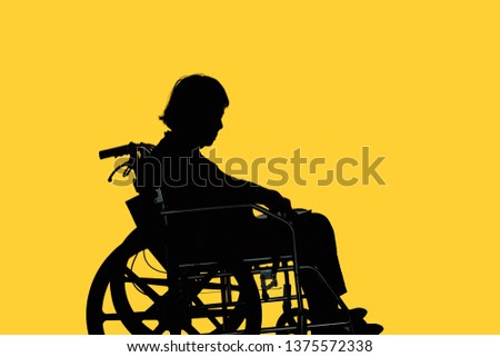 Silhouette of Disabled and dejected elderly woman sitting in her wheelchair