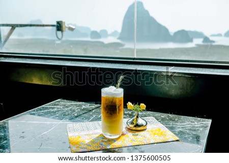 Ice coconut coffee latte on the marble table with background landscape of Phang Nga Bay or Ao Phang Nga National Park at Samet Nangshe view point.