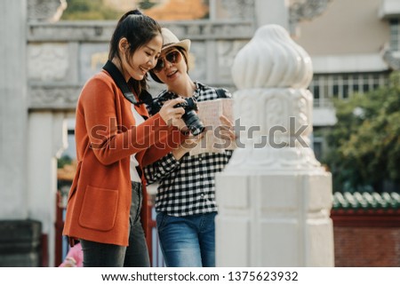 Group of Asian women standing close looking check photo in camera while traveling at chinese style park in beijing temple. Lifestyle friends tourist holiday. female on bridge by white stone railing
