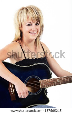 Beautiful young blonde caucasian woman playing a blue acoustic guitar against a white background