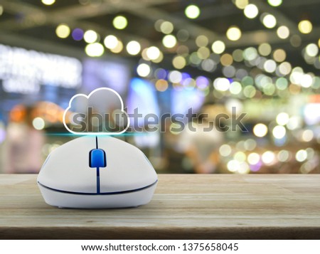 Cloud icon with copy space and wireless computer mouse on wooden table over blur light and shadow of shopping mall, Cloud computing concept