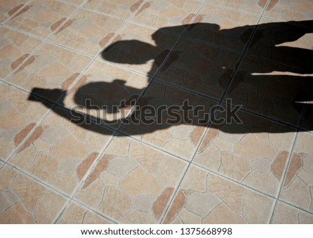 The shadow of two boys using mobile phones to take pictures