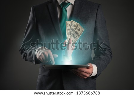 Get money online. Money cashback from internet store. Online payment or deal. Businessman with a tablet computer in hands and hand with cash. Royalty-Free Stock Photo #1375686788