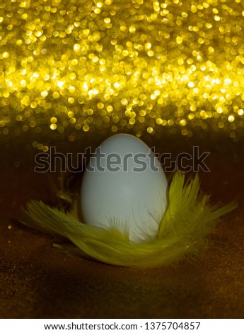 Egg on yellow feathers and golden background. Vertical image.