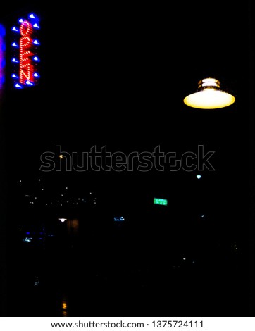 Open neon sign in blue and red with a lantern in the window. Reflection on a window of a neon open sign.