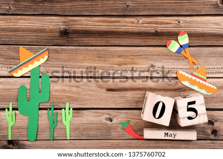 Paper cactuses with hat, maracas and cube calendar on wooden table
