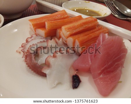 Squid and fish sushi with crab sticks placed on a white plate, focusing on placing food on the back and taking pictures from the empty space from entering for food.