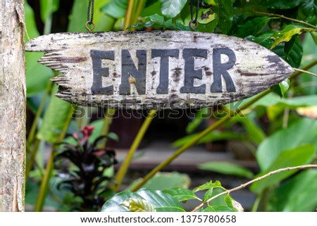 Text enter on a wooden board in a rainforest jungle of tropical Bali island, Indonesia. Enter wooden sign inscription in the asian tropics. Close up