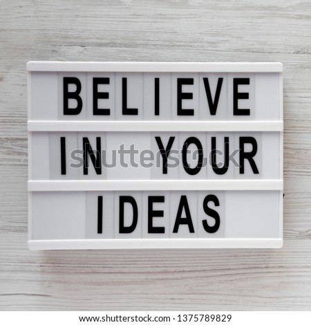 'Believe in your ideas' words on modern board over white wooden surface. Flat lay, from above, overhead. 