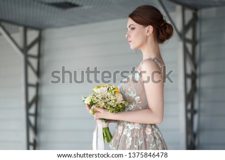 Portrait of an elegant bride in an unusual chic dress with a bouquet in her hands.