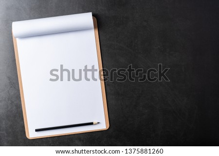 Design concept - top view of white A4 flipped paper with brown clipboard on black stone background for mockup. real photo, not 3D render