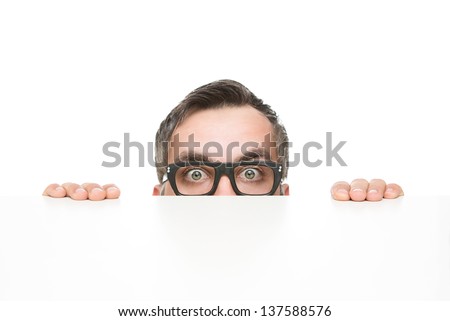 Funny nerd peeking from behind the desk isolated on white background with copy space