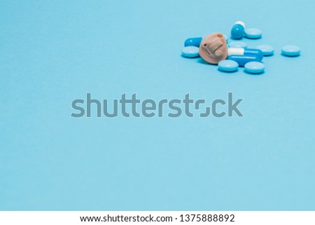 Hearing aid and blue pills on blue background. Medical, pharmacy and healthcare concept. Copy space. Empty place for text or logo.