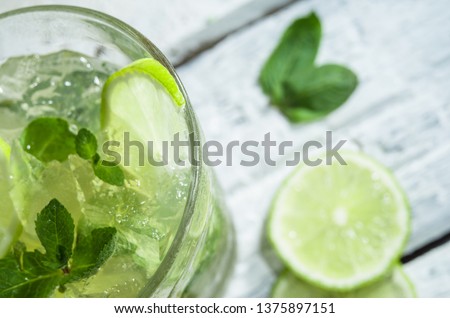 Mojito cocktail with slices of lime and mint leaves in highball glass on a wood table. White background. Royalty-Free Stock Photo #1375897151