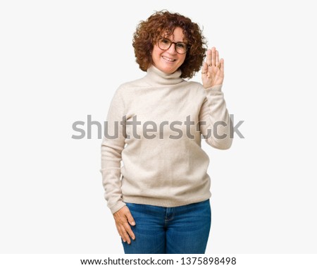 Beautiful middle ager senior woman wearing turtleneck sweater and glasses over isolated background Waiving saying hello happy and smiling, friendly welcome gesture