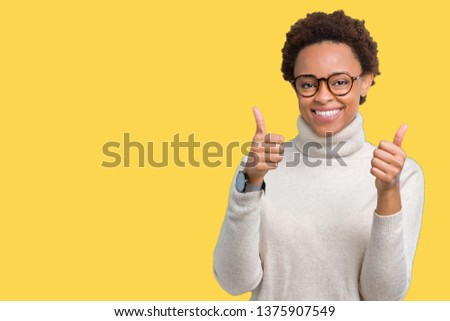 Young beautiful african american woman wearing glasses over isolated background success sign doing positive gesture with hand, thumbs up smiling and happy. Looking at the camera 