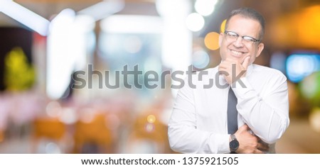 Middle age bussines arab man wearing glasses over isolated background looking confident at the camera with smile with crossed arms and hand raised on chin. Thinking positive.
