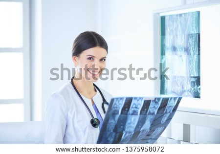Young female doctor with stethoscope examining X-ray at doctor's office