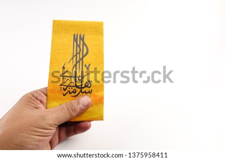 Money packet during Eid Fitr on white. Arabic characters means Happy Eid Mubarak.