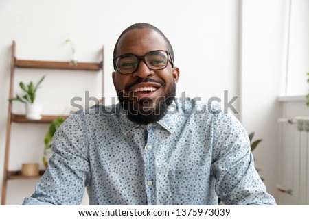Happy african black business man looking at camera webcam making conference video call, e-coaching, talking  online job interview, recording blog webinar, communicating with client, portrait Royalty-Free Stock Photo #1375973039