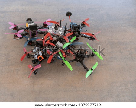 A bunch of racing drones on a table, all equipped with a camera and carbon frames.