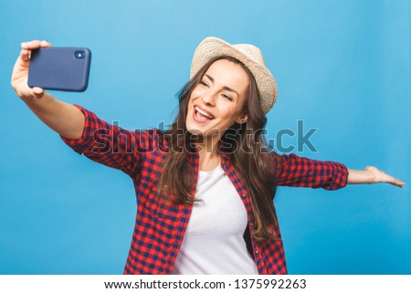 Charming young woman in white hat travel and take selfie on front camera smartphone isolated on blue pink background.
