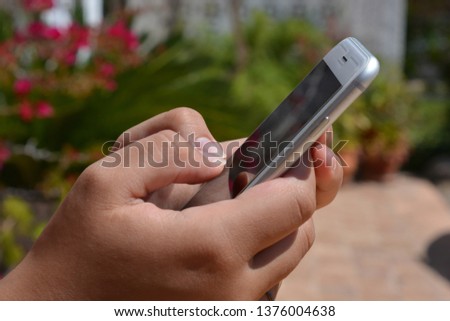 Millennial woman using mobile phone outdoors in the summer, closeup of hands holding phone
