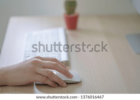 hand hold mouse with keyboard and cactus on wooden table