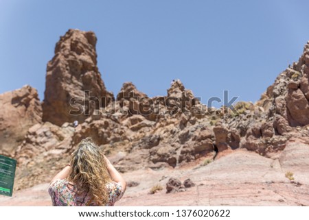 A mature blonde tourist is taking pictures of some volcanic rocks, Tenerife island, Spain