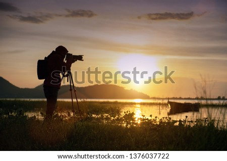 Travel photographer taking a photo with nature the lake in sunset to nightlife with camera on tripod, Focusing attention nature mountain view and lake,  Natural photography relaxing concept.