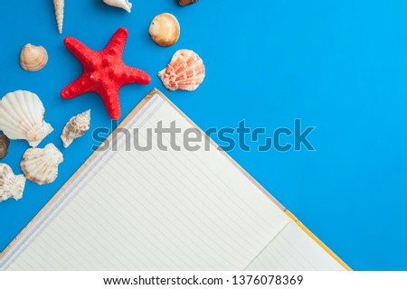 Open empty notebook on a blue background with shells and starfish. Postcard, tourism, space for text