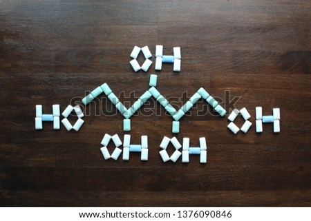 Chewing Gum laid on the brown wooden table in the shape of Xylitol's Chemical Formula. Xylitol is a sugar alcohol used as a sugar substitute. 