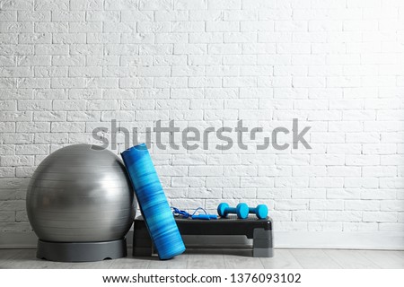 Set of fitness inventory on floor near brick wall. Space for text Royalty-Free Stock Photo #1376093102