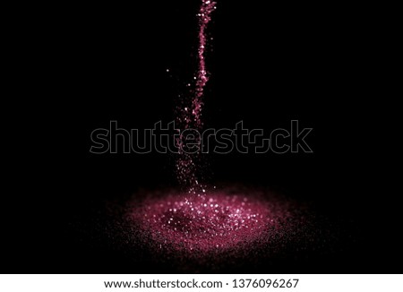 Sprinkling rose glitter on black background, bokeh effect