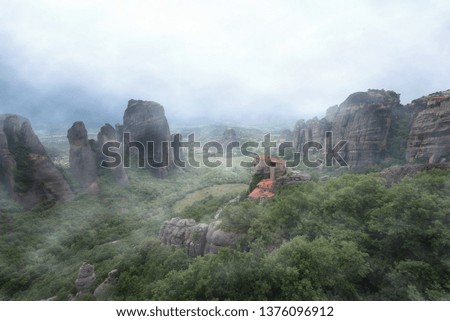 Magnificent spring landscape.Orthodox Monastery of Rousanou (St. Barbara), immense monolithic pillar, green foliage at the background of stone wall in Meteora, Pindos Mountains, Thessaly, Greece.