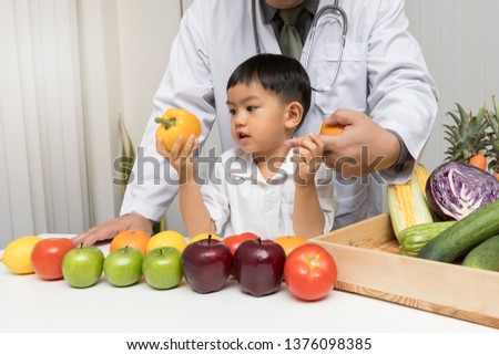 A boy and doctor happy to have healthy food. Kid learning about nutrition with doctor to choose eating fresh fruits and vegetables.