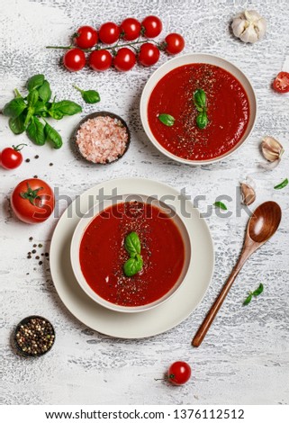 Traditional Spanish cold tomato soup gazpacho in a white bowl on a grey stone background. Traditional Spanish food. Concept of Spanish cold soup made of ripe tomatoes. Copy space, top view soup. 