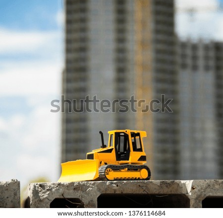 Toy bulldozer on the concrete block in the construction site. Building and architecture.