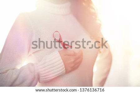 The red ribbon of the girl. The girl is holding a red ribbon. Health concept red ribbon. Breast cancer.
