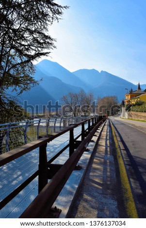 Road along the Adige River in Verona region with mountain range in the background, Italy