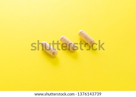 Herbal medical capsule on a yellow background. natural vitamin supplements in food. top view
