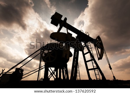 Operating oil and gas well contour, profiled on sky with storm clouds Royalty-Free Stock Photo #137620592