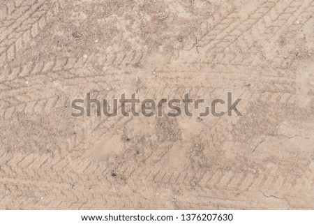 Car wheel on a dirt road on the brown dry soil ground texture background.
