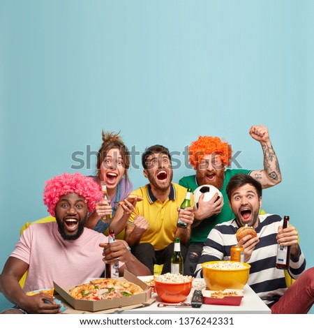 Photo of friends watch soccer game, celebrate goal, clench fists, enjoy watching sport competition, have delicious snack, drink cold beer, spend spare time at home. Pastime and entertainment Royalty-Free Stock Photo #1376242331
