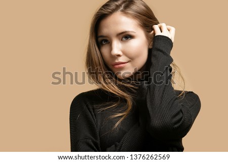 Fashion portrait of mysterious pretty lady wearing black knitted sweater. Melancholy and autumn concept. Sweet adorable girl posing isolated on beige background