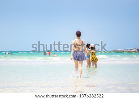 Asian woman walking on sand beach to sea ocean in Phuket island on Thailand, Asian girl group playing and relaxing on summer holiday, sea beach on blue sky background, vacation time journey.
