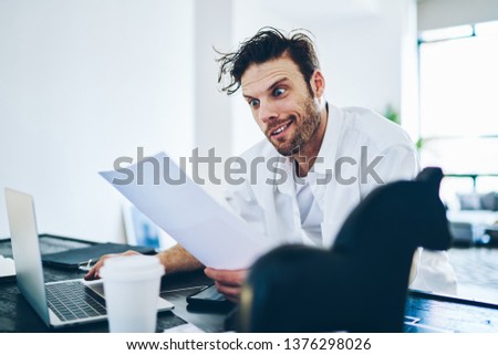 Emotional shocked editor feeling surprised while reading article for publication sitting at his working place with laptop computer, confused caucasian businessman stressed with financial report
